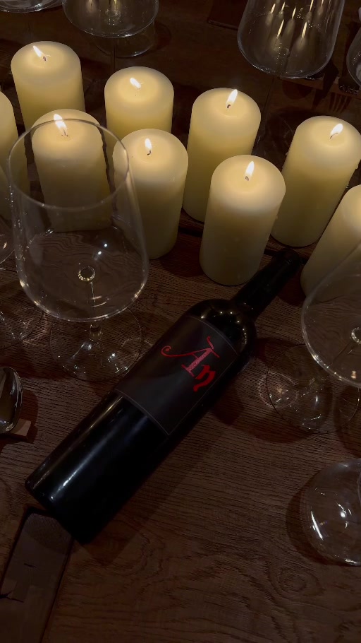 Una botella de Ànima Negra entre copas y velas en la mesa de Es Celler